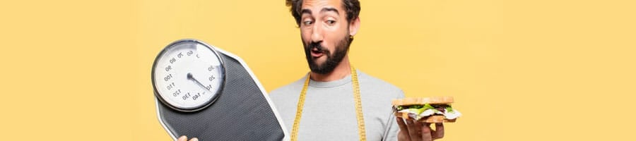 man holding up a weighing scale and a sandwich while thinking