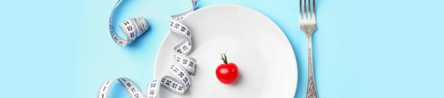 measuring tape and tomato on a plate with a fork beside