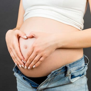 woman pregnant forming a heart using her hands on her stomach