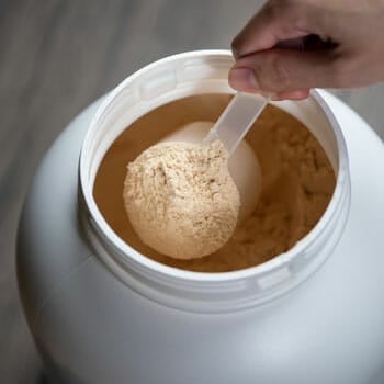 container and scooper filled with protein powder