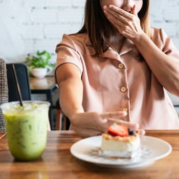 woman pushing away a plate of sweets