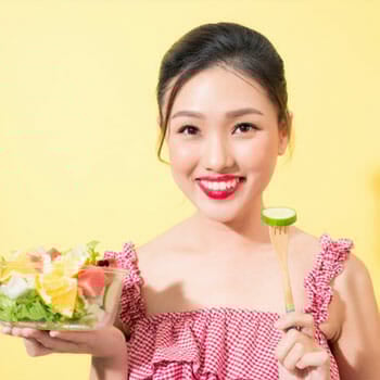 woman holding up a salad bowl and a fork