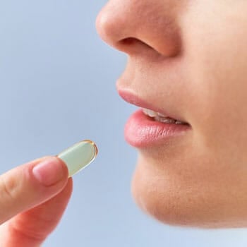 female placing a fish oil pill in her mouth