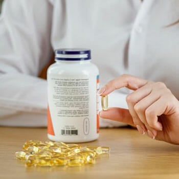 bottle of capsule on table and a hand holding a capsule