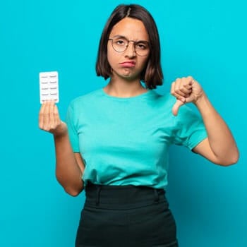 woman upset with her thumbs down holding a sachet of pills