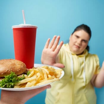 plate with burger and fries and a woman saying no to it