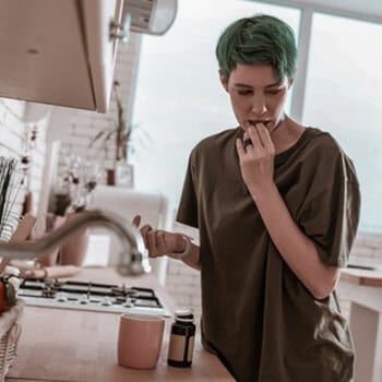 woman hiding while taking pills