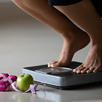 Woman stepping on weighing scale to cheat her weight