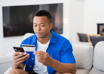 Man holding card and smartphone ordering online