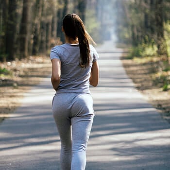 Woman brisk walking in a green park