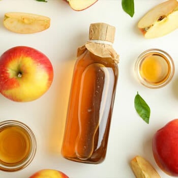 bottle filled of apple cider vinegar and fresh apples beside