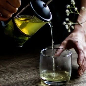 pressed green tea getting poured in a drinking glass