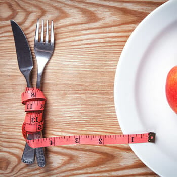 fork and knife tied in a measuring tape and a plate with a fresh apple