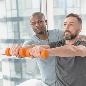 trainer assisting a man lifting dumbbells