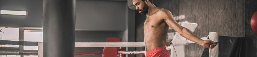 shirtless man in a gym jumping rope