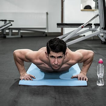 shirtless man in a pushup position on a yoga mat