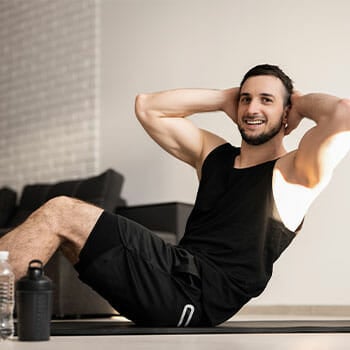 man smiling while doing crunches at home