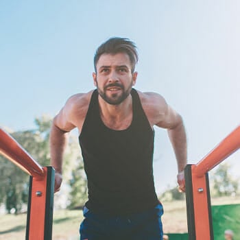 man doing bar dips in a park