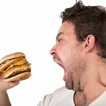 man holding up a big burger with his mouth wide open