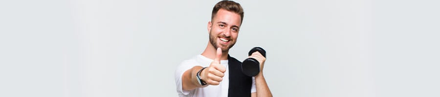 man smiling while holding up a thumbs up and a dumbbell
