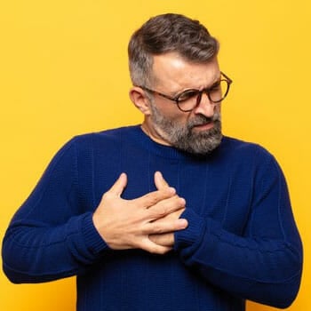 aged man with both of his hands in his chest in pain