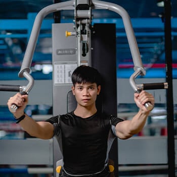 man using a pec deck machine in a gym