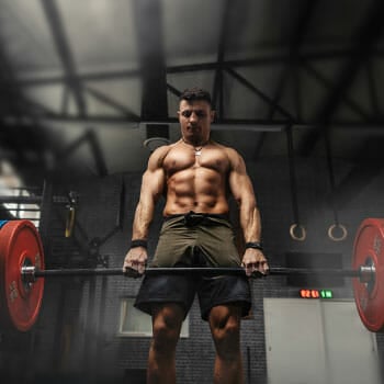 shirtless man weightlifting a heavy barbell