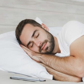 bearded man sleeping peacefully on his side in bed