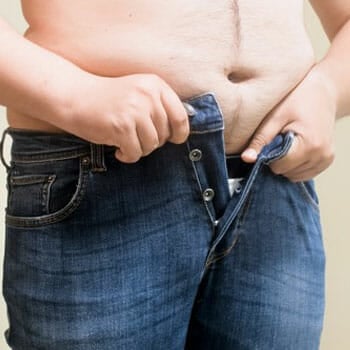 person with a big fat belly trying to close his jeans