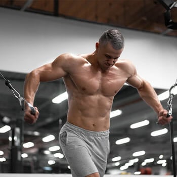 shirtless man doing standing cable flys