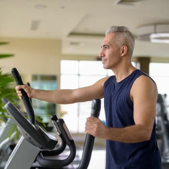 man in a gym working out in an elliptical