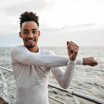 man doing arm stretches outdoors smiling