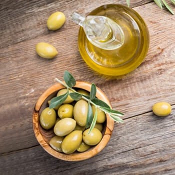 bowl filled with olives and a bottle of oil beside