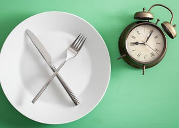 plate with fork and knife and a clock beside