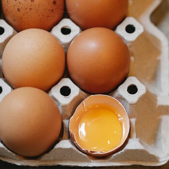 fresh eggs and a cracked egg in a tray