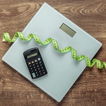 calculator and measuring tape on a weighing scale