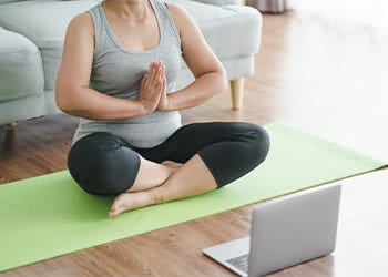 woman in a yoga position in a at in front of a laptop