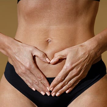 woman shaping a heart on her bare stomach