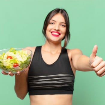 woman smiling while holding a salad bowl and a thumbs up