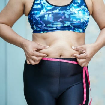 woman in gym clothes pinching her belly