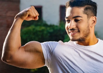 A man flexing his bicep muscles outside