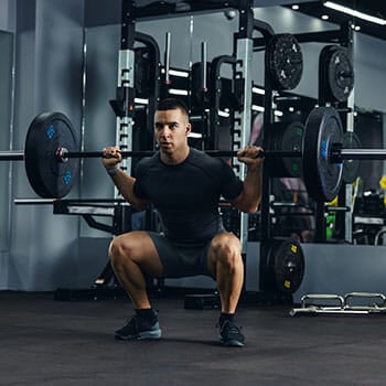 man in a gym practicing back squats