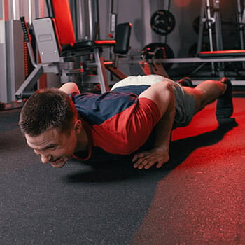 man in a regular pushup position in a gym