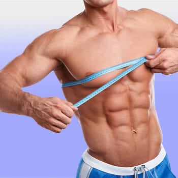 shirtless man showing his abs while using a measuring tape on his chest