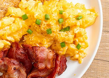 seasoned scrambled eggs and fried bacon in a plate