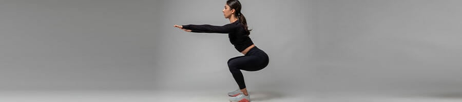 woman in squat position in a grey background