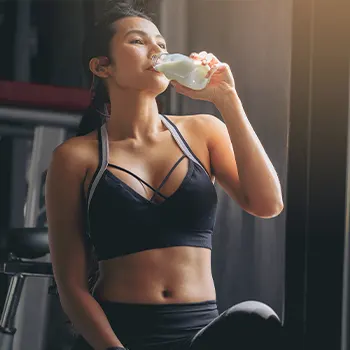 woman in gym clothes drinking from her tumbler