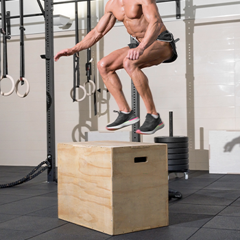 man doing box jumps in a gym