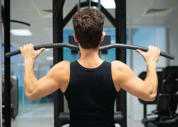 man in a gym doing a lat pulldown