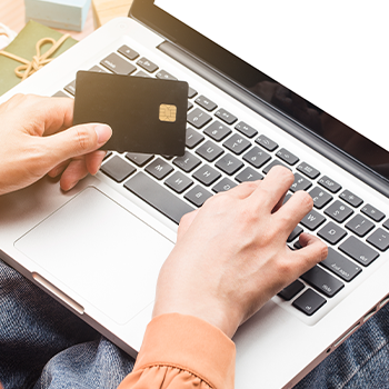 hand view of a person typing and holding a credit card